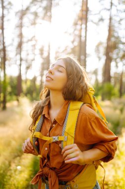 Dişi sırt çantalı turist ağaçlara bakıyor ve doğa manzarasının tadını çıkarıyor. Aktif yaşam tarzı. Yürüyüş.
