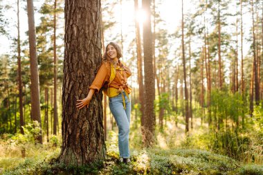Dişi sırt çantalı turist ağaçlara bakıyor ve doğa manzarasının tadını çıkarıyor. Aktif yaşam tarzı. Yürüyüş.