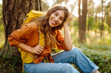 Dişi sırt çantalı turist ağaçlara bakıyor ve doğa manzarasının tadını çıkarıyor. Aktif yaşam tarzı. Yürüyüş.