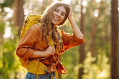 Dişi sırt çantalı turist ağaçlara bakıyor ve doğa manzarasının tadını çıkarıyor. Aktif yaşam tarzı. Yürüyüş.