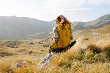 Sırt çantalı gezgin kadın dağda yürüyor. Macera aktif. Manzaranın tadını çıkar.