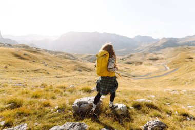 Sırt çantalı gezgin kadın dağda yürüyor. Macera aktif. Manzaranın tadını çıkar.