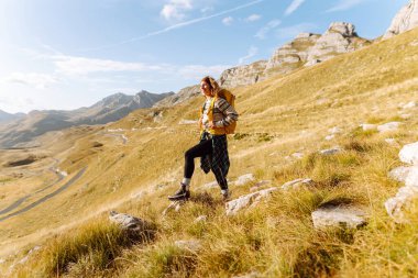 Sırt çantalı gezgin kadın dağda yürüyor. Macera aktif. Manzaranın tadını çıkar.
