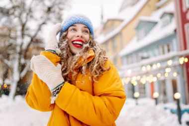 Şenlikli dekorasyon ve ışıklarla süslenmiş genç bir kadın sokakta yürüyor. Moda tarzı. Kış tatili.