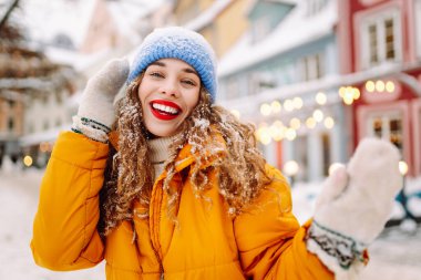 Şenlikli dekorasyon ve ışıklarla süslenmiş genç bir kadın sokakta yürüyor. Moda tarzı. Kış tatili.