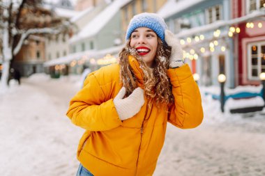Şenlikli dekorasyon ve ışıklarla süslenmiş genç bir kadın sokakta yürüyor. Moda tarzı. Kış tatili.