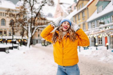 Şenlikli dekorasyon ve ışıklarla süslenmiş genç bir kadın sokakta yürüyor. Moda tarzı. Kış tatili.