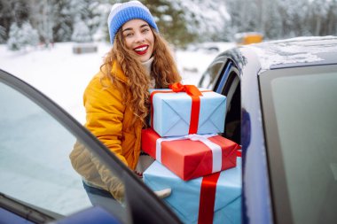 Genç bir kadın arabaya yılbaşı hediyesi koyar. Mutlu kadın Noel için hazırlanıyor. Sürpriz kavramı, alışveriş..