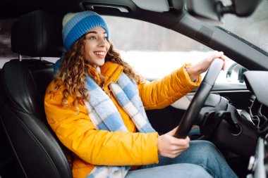 Gündüz vakti kış yolunda araba süren genç bir kadın. Ulaşım konsepti, yaşam tarzı. Kış tatili.