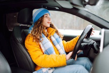 Gündüz vakti kış yolunda araba süren genç bir kadın. Ulaşım konsepti, yaşam tarzı. Kış tatili.
