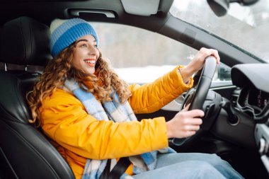 Gündüz vakti kış yolunda araba süren genç bir kadın. Ulaşım konsepti, yaşam tarzı. Kış tatili.