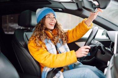 Gündüz vakti kış yolunda araba süren genç bir kadın. Ulaşım konsepti, yaşam tarzı. Kış tatili.