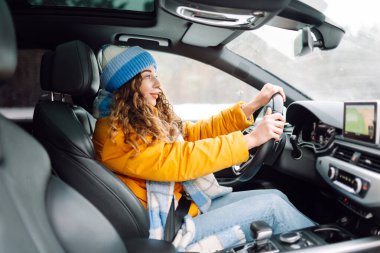 Gündüz vakti kış yolunda araba süren genç bir kadın. Ulaşım konsepti, yaşam tarzı. Kış tatili.