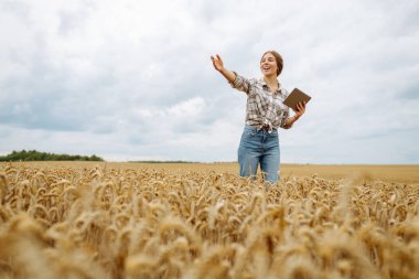 Akıllı çiftlik. Tarlada tableti olan genç bir kadın çiftçi. Tarım, bahçıvanlık, iş ya da ekoloji konsepti. Büyüme dinamikleri.