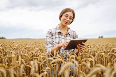 Akıllı çiftlik. Tarlada tableti olan genç bir kadın çiftçi. Tarım, bahçıvanlık, iş ya da ekoloji konsepti. Büyüme dinamikleri.