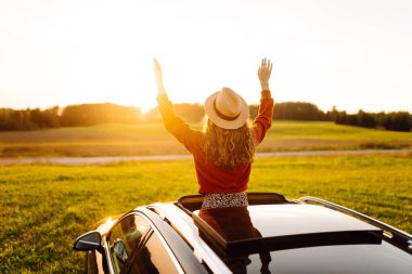 Rahat kadın arabanın penceresinden gün batımını seyretmeyi sever. Seyahat konsepti, tatil. Maceraya doğru.
