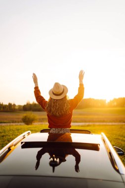 Rahat kadın arabanın penceresinden gün batımını seyretmeyi sever. Seyahat konsepti, tatil. Maceraya doğru.