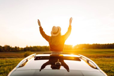 Rahat kadın arabanın penceresinden gün batımını seyretmeyi sever. Seyahat konsepti, tatil. Maceraya doğru.