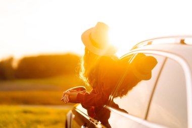 Rahat kadın arabanın penceresinden gün batımını seyretmeyi sever. Seyahat konsepti, tatil. Maceraya doğru.