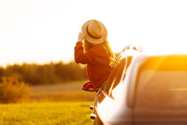 Rahat kadın arabanın penceresinden gün batımını seyretmeyi sever. Seyahat konsepti, tatil. Maceraya doğru.