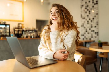 Kafede dizüstü bilgisayarla çalışan genç bir kadın. Serbest, çevrimiçi kurs. İnternetten alışveriş.