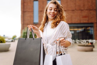 Şehir caddesinde alışveriş torbalarıyla yürüyen güzel bir genç kadının portresi. Kara Cuma. Kış tatili Satışlar, alışverişler.