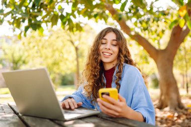 Göl kenarındaki bir kafede dizüstü bilgisayarı ve telefonu olan mutlu bir kadın. İş, blog yazma, serbest çalışma.