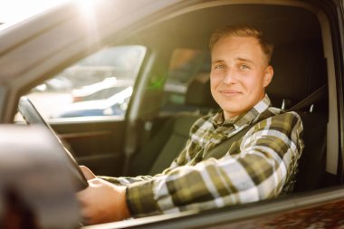 Arabasının sürücü koltuğunda oturan yakışıklı genç adamın portresi. Araba yolculuğu, yaşam tarzı konsepti..