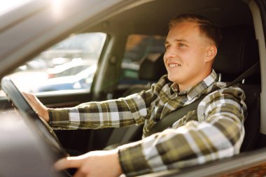 Arabasının sürücü koltuğunda oturan yakışıklı genç adamın portresi. Araba yolculuğu, yaşam tarzı konsepti..