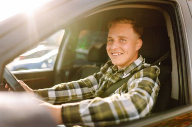 Arabasının sürücü koltuğunda oturan yakışıklı genç adamın portresi. Araba yolculuğu, yaşam tarzı konsepti..