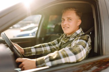 Arabasının sürücü koltuğunda oturan yakışıklı genç adamın portresi. Araba yolculuğu, yaşam tarzı konsepti..