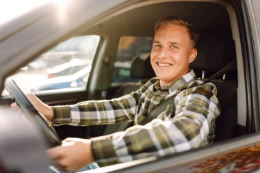 Arabasının sürücü koltuğunda oturan yakışıklı genç adamın portresi. Araba yolculuğu, yaşam tarzı konsepti..