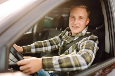 Arabasının sürücü koltuğunda oturan yakışıklı genç adamın portresi. Araba yolculuğu, yaşam tarzı konsepti..