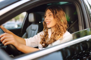 Genç bir kadın güvenli bir şekilde araç kullanıyor, emniyet kemeri takılı. Otomobil yolculuğu.