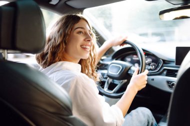 Genç bir kadın güvenli bir şekilde araç kullanıyor, emniyet kemeri takılı. Otomobil yolculuğu.