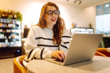 Rahat bir kafede otururken bilgisayarını kullanan serbest çalışan bir kadın. İnternetten alışveriş.