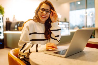 Rahat bir kafede otururken bilgisayarını kullanan serbest çalışan bir kadın. İnternetten alışveriş.