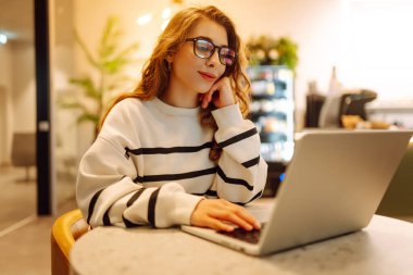 Rahat bir kafede otururken bilgisayarını kullanan serbest çalışan bir kadın. İnternetten alışveriş.