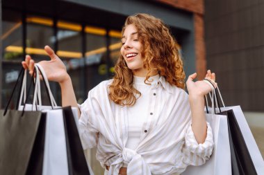 Alışveriş merkezinden alışverişlerle çıkan güzel bir kadın. Tüketim, moda, alışverişler, satış, yaşam tarzı konsepti.