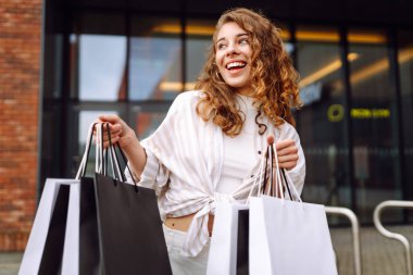Alışveriş merkezinden alışverişlerle çıkan güzel bir kadın. Tüketim, moda, alışverişler, satış, yaşam tarzı konsepti.