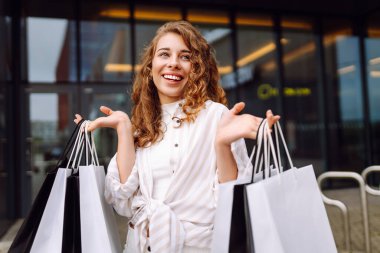 Alışveriş merkezinden alışverişlerle çıkan güzel bir kadın. Tüketim, moda, alışverişler, satış, yaşam tarzı konsepti.