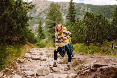 Gezgin kadın sırt çantasıyla kayalık bir yolda yürüyor. Seyahat, macera. Etkin bir yaşam biçimi kavramı.
