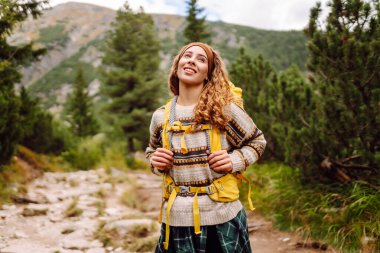 Gezgin kadın sırt çantasıyla kayalık bir yolda yürüyor. Seyahat, macera. Etkin bir yaşam biçimi kavramı.