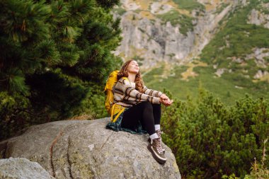 Gezgin kadın sırt çantasıyla kayalık bir yolda yürüyor. Seyahat, macera. Etkin bir yaşam biçimi kavramı.