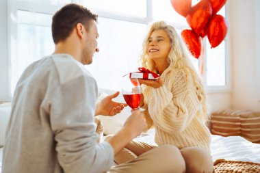 Mutlu çift evde kırmızı şarap içiyor. Birlikte romantik bir gün. Boş zaman, kutlama ve Sevgililer Günü konsepti.