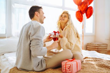 Mutlu çift evde kırmızı şarap içiyor. Birlikte romantik bir gün. Boş zaman, kutlama ve Sevgililer Günü konsepti.