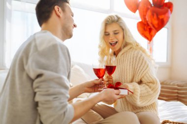 Mutlu çift evde kırmızı şarap içiyor. Birlikte romantik bir gün. Boş zaman, kutlama ve Sevgililer Günü konsepti.