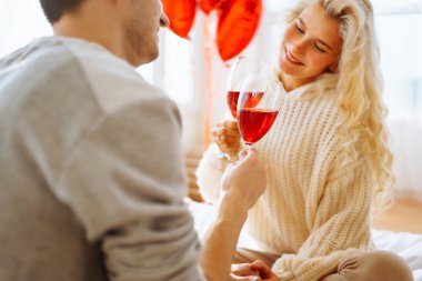 Mutlu çift evde kırmızı şarap içiyor. Birlikte romantik bir gün. Boş zaman, kutlama ve Sevgililer Günü konsepti.