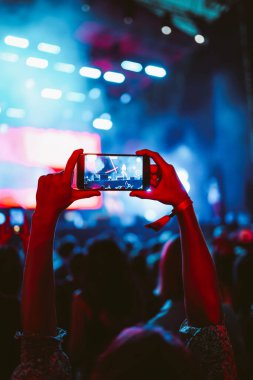 Telefon kayıtlarıyla birlikte canlı müzik festivali. Akıllı telefonla fotoğraf çeken insanlar..