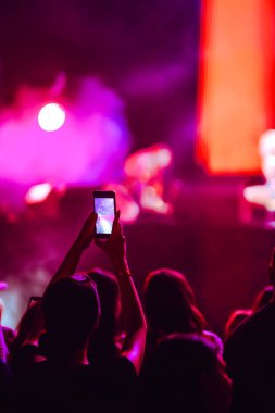 Telefon kayıtlarıyla birlikte canlı müzik festivali. Akıllı telefonla fotoğraf çeken insanlar..